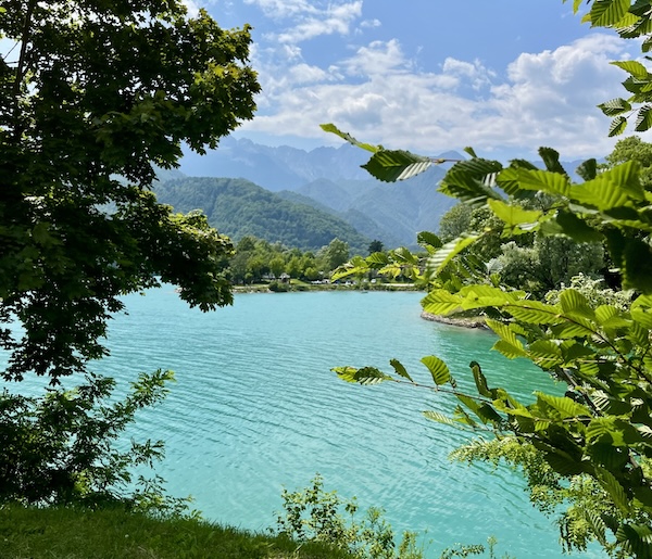 Turquoise waters of Lake Barcis surrounded by forested mountains in Friuli Venezia Giulia.