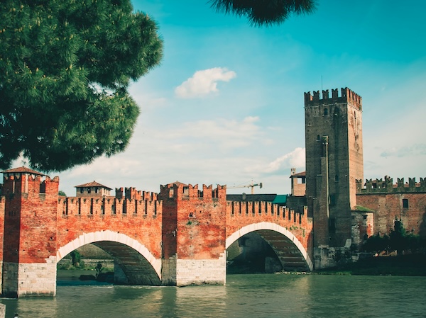 Verona’s historic Castelvecchio Bridge across the Adige River, with medieval brick arches and tower under a clear sky in northern Italy.